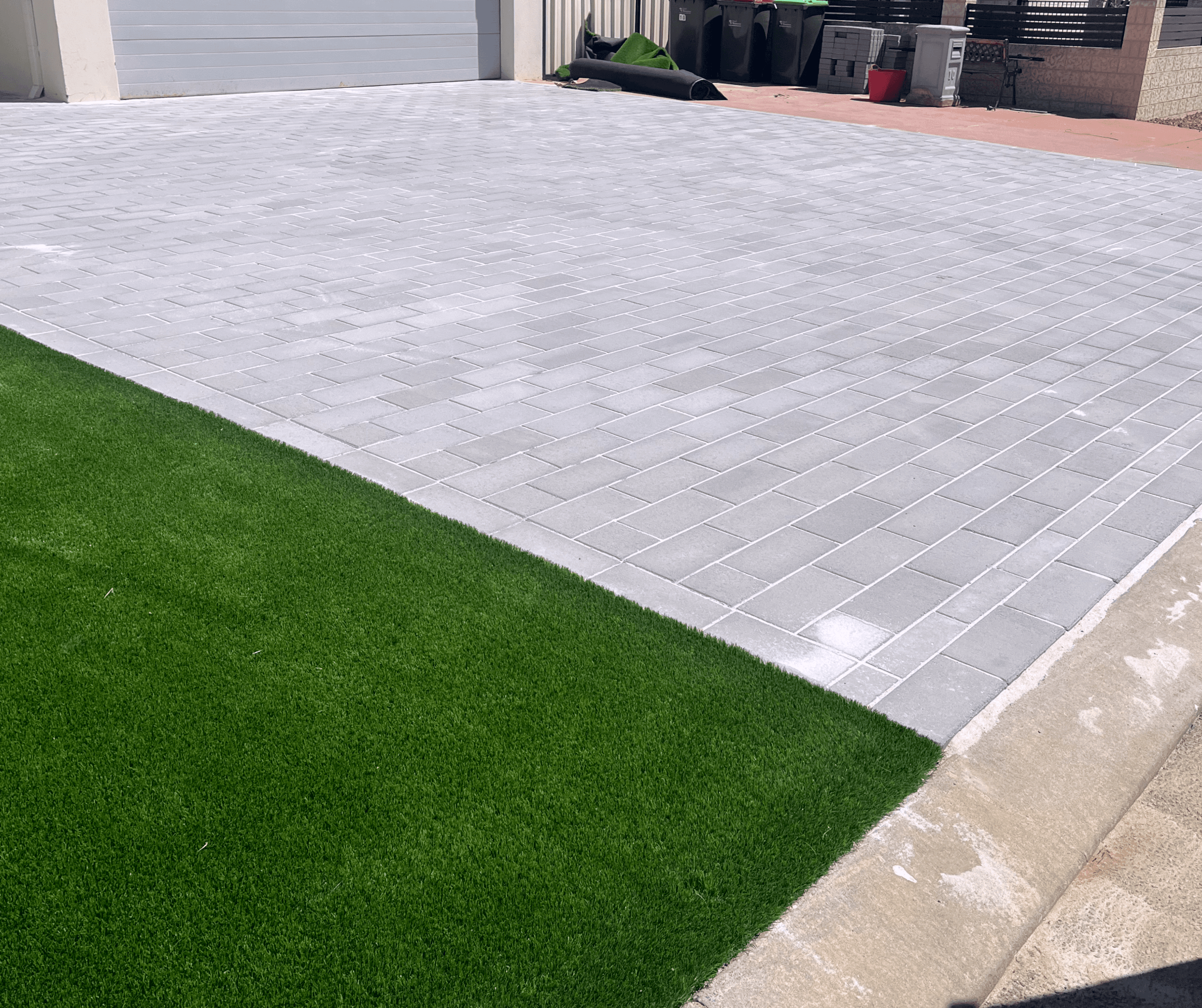 Light grey pavers meeting a straight edge of artificial grass
