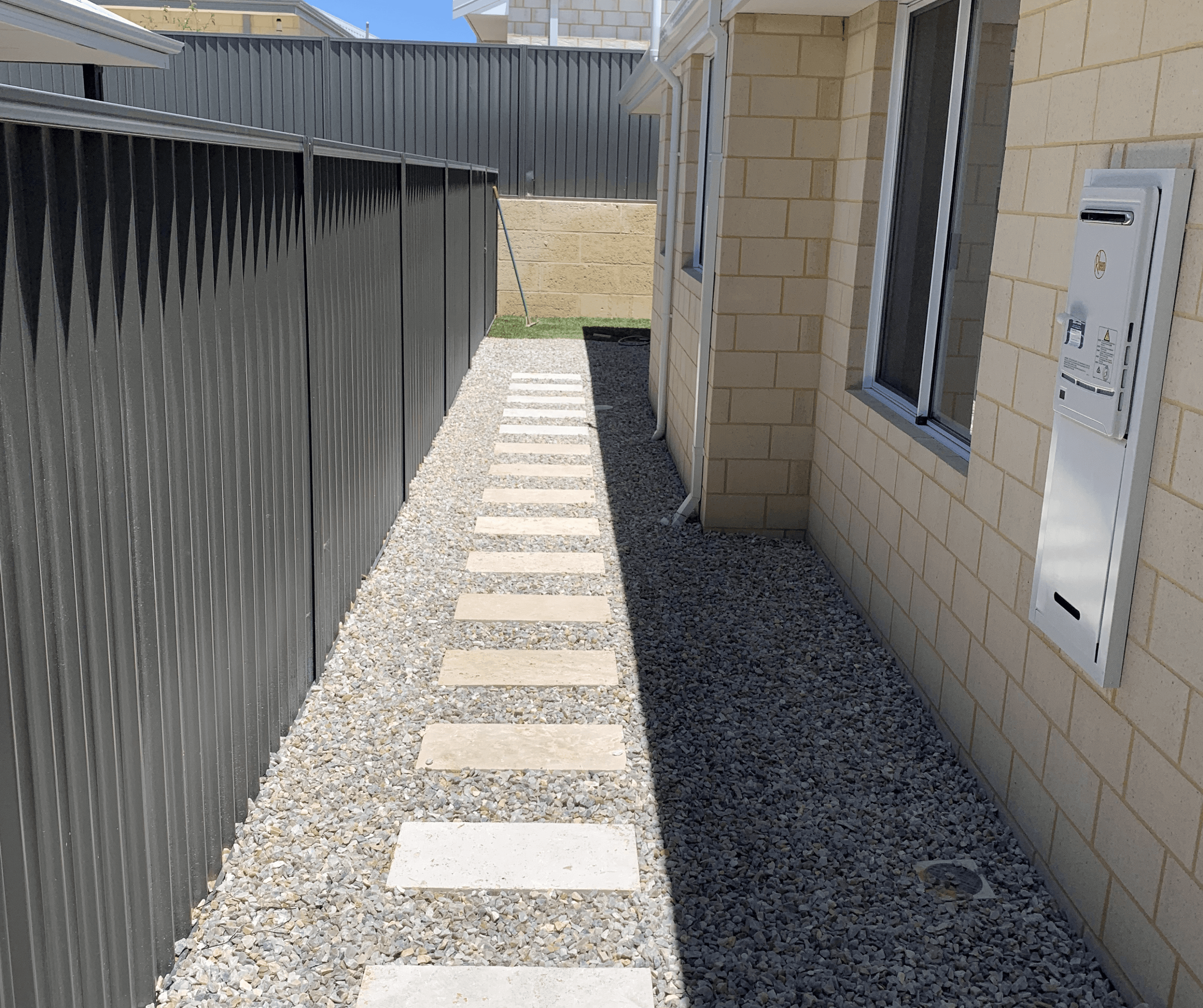 Pale stepping pavers set in grey gravel along a side passage