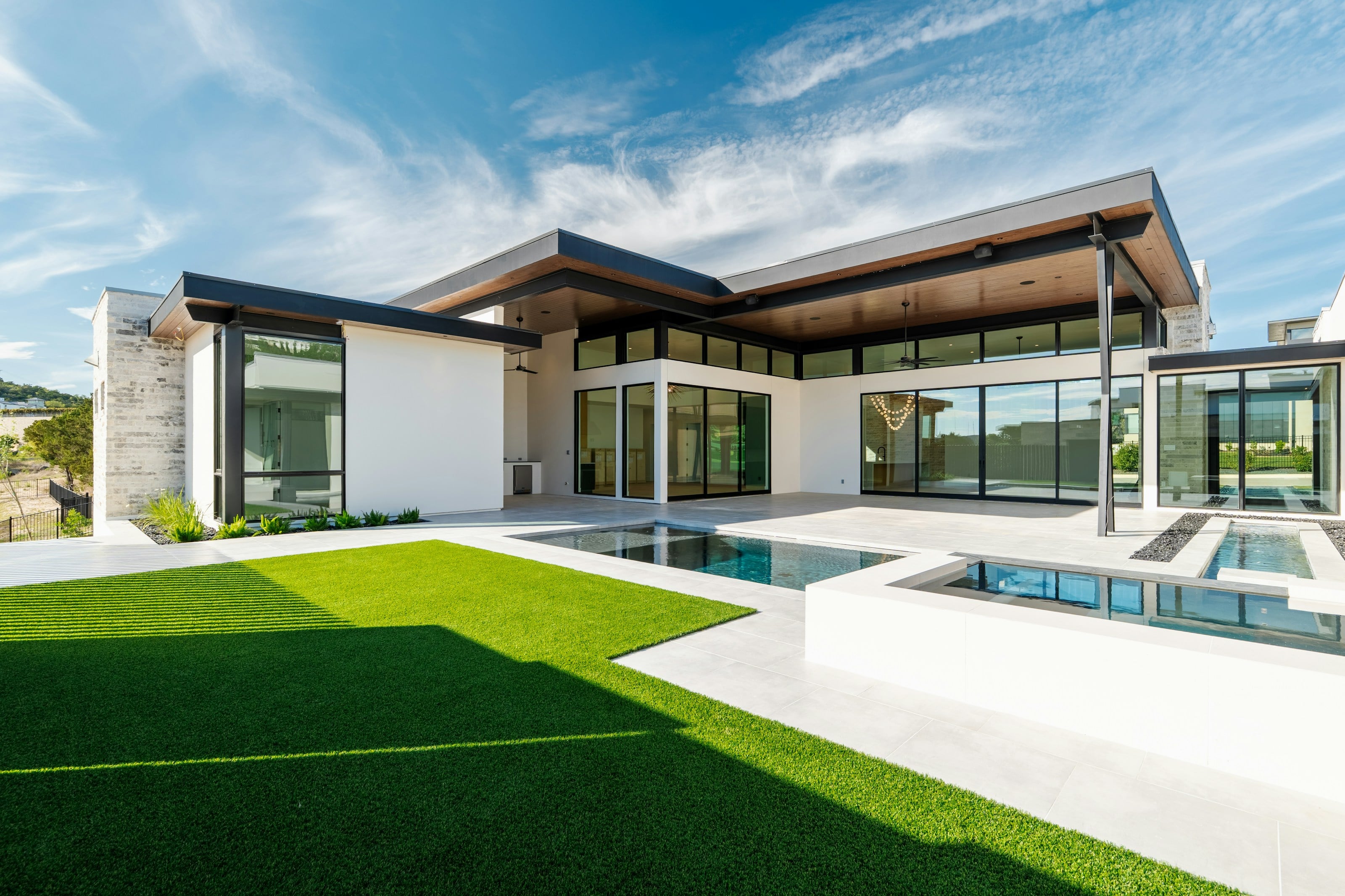 Contemporary home with a pool and a wide, even green lawn under a blue sky