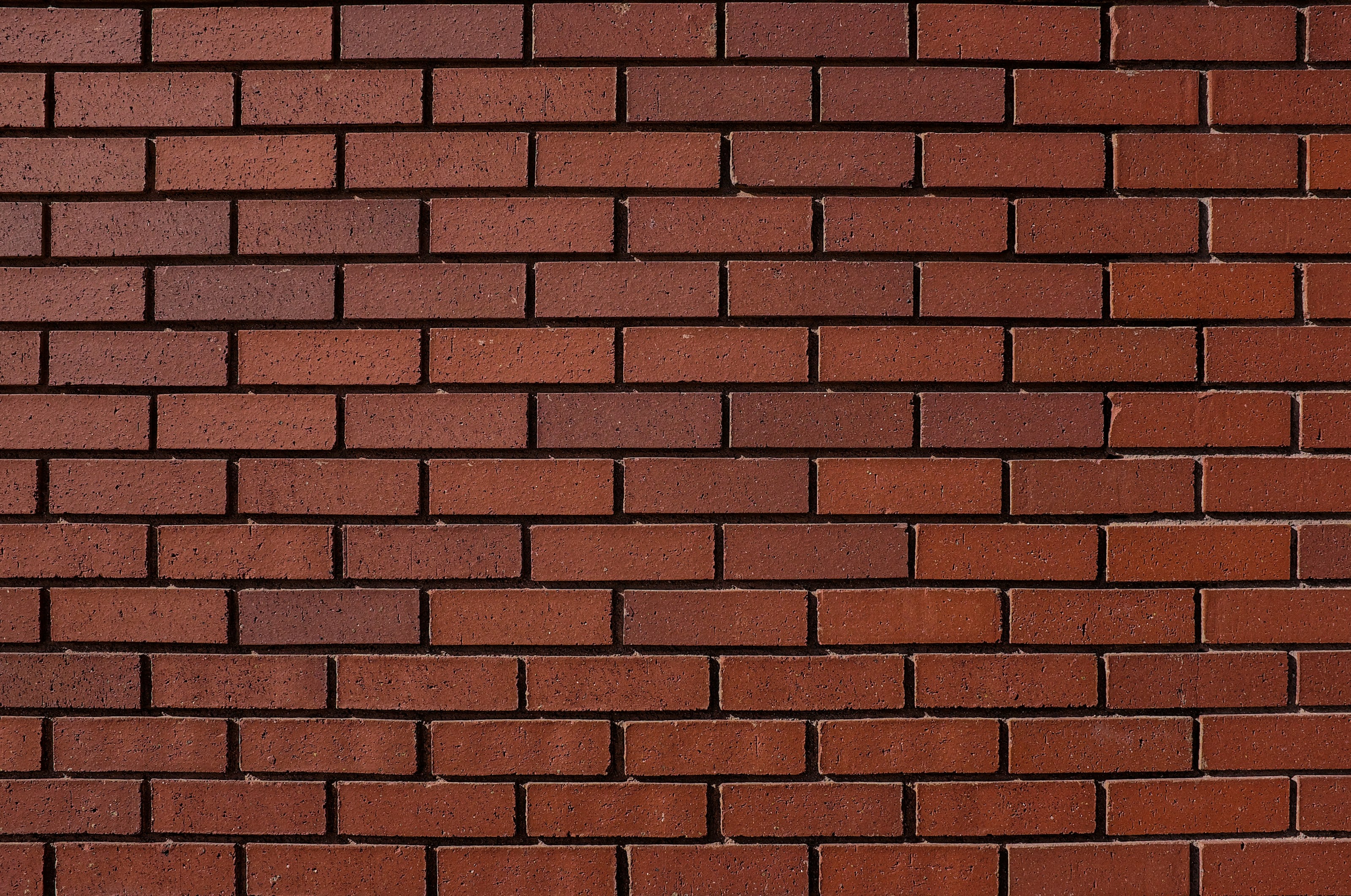 Clean red brick wall laid in an even stretcher bond with neat mortar lines