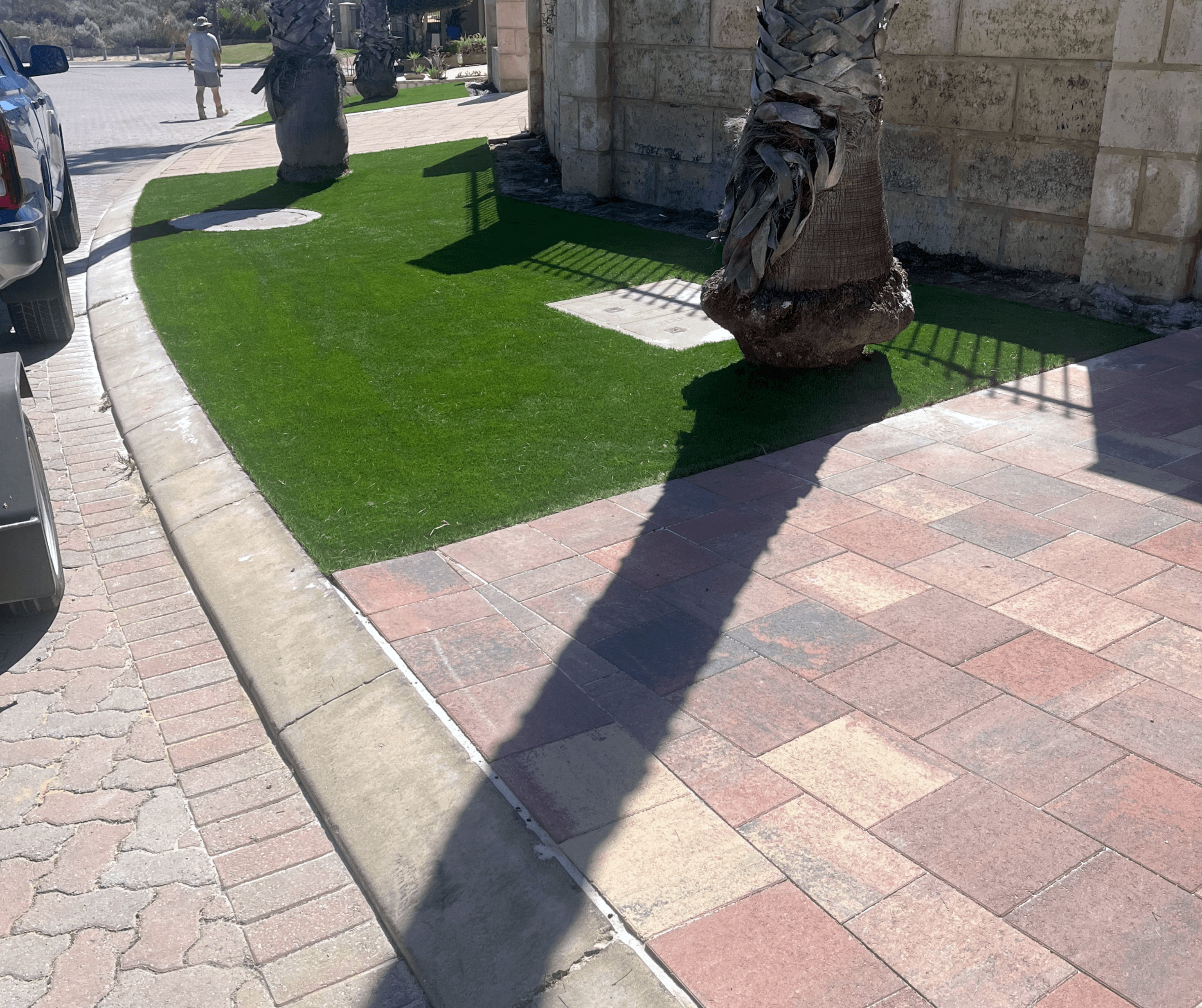 Artificial grass following a curved kerb beside red blend paving