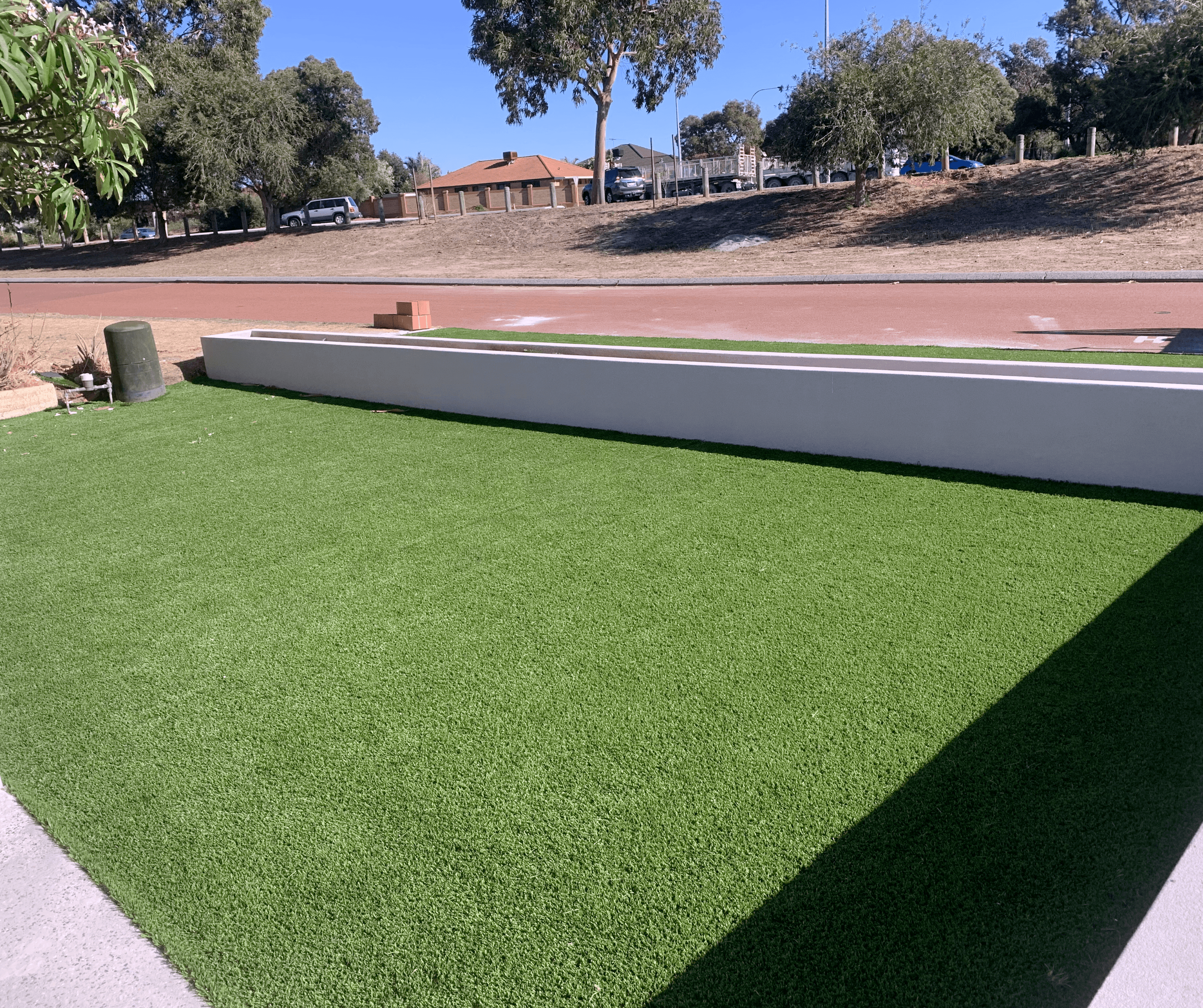 Artificial grass on a verge below a low rendered wall